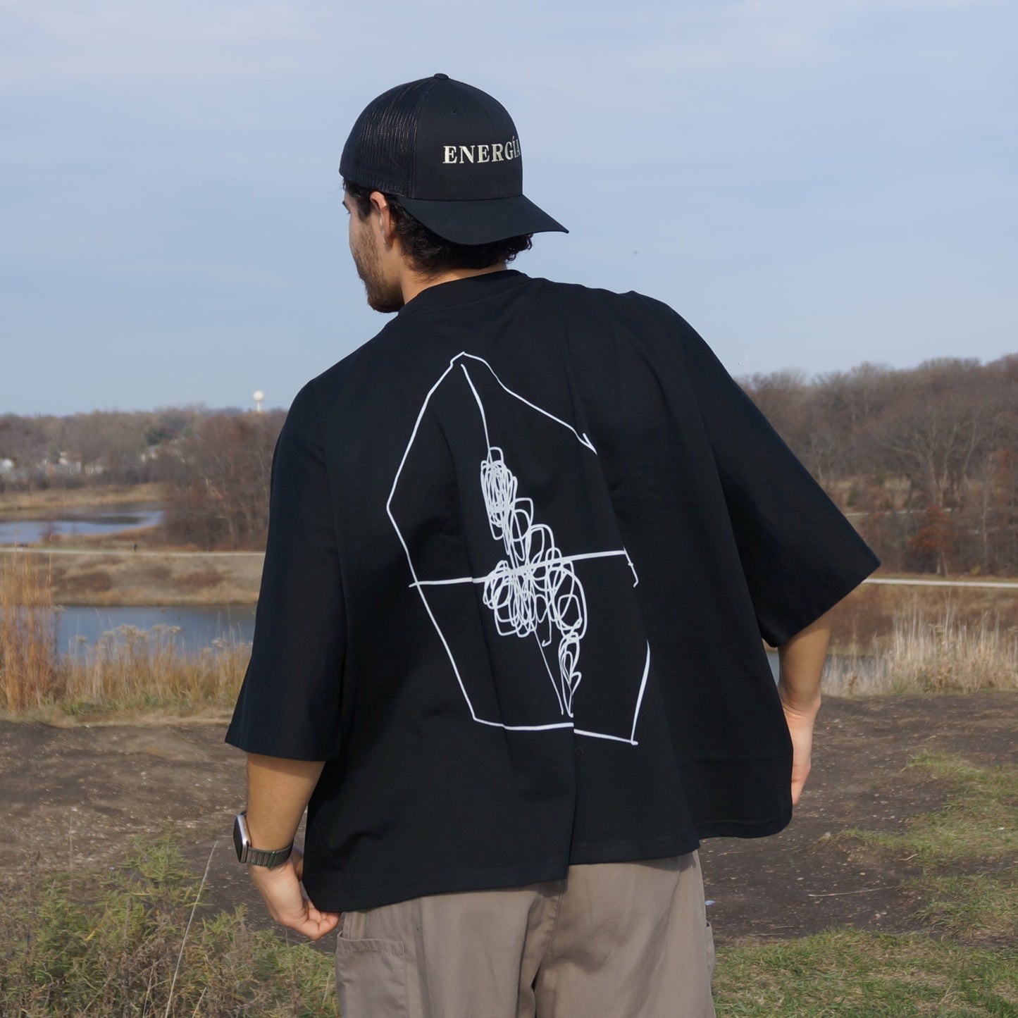 Backside of guy wearing an Era of Energy ENERGÍA - Oversize One-piece Pattern Cut Boxy Tee out in nature